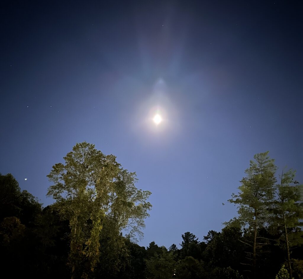 Angelic form surrounding full moon in night sky
